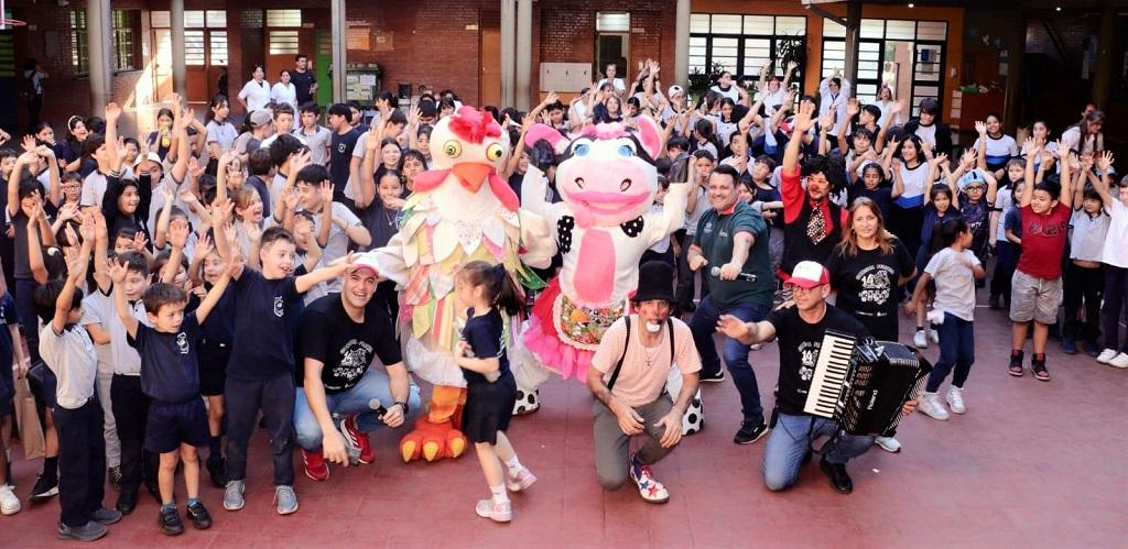 Alumnos de la Escuela 110 y el equipo de Gurises Felices saludan a la cámara en el patio de la escuela.