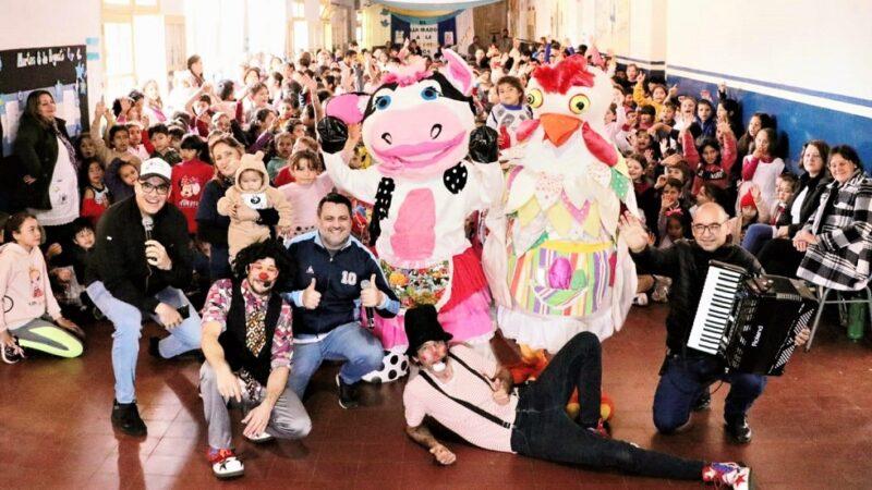 Equipo de Gurises con los niños y docentes saludan sonrientes a la cámara.