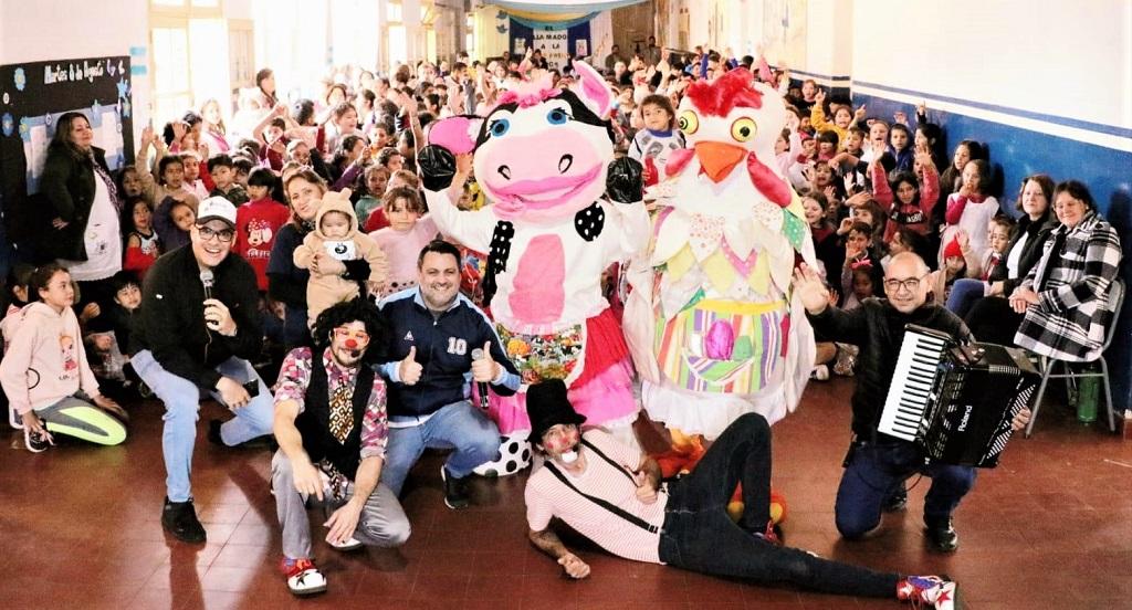 Equipo de Gurises con los niños y docentes saludan sonrientes a la cámara.