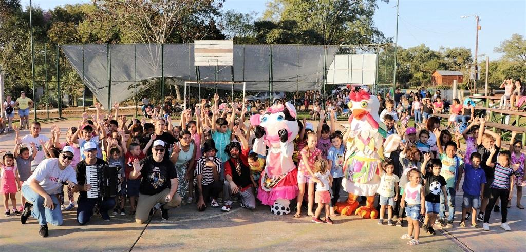 Niños y equipo de Gurises Felices saludan sonrientes en el playón del deportivo durante los festejos del cumpleaños de Profundidad.