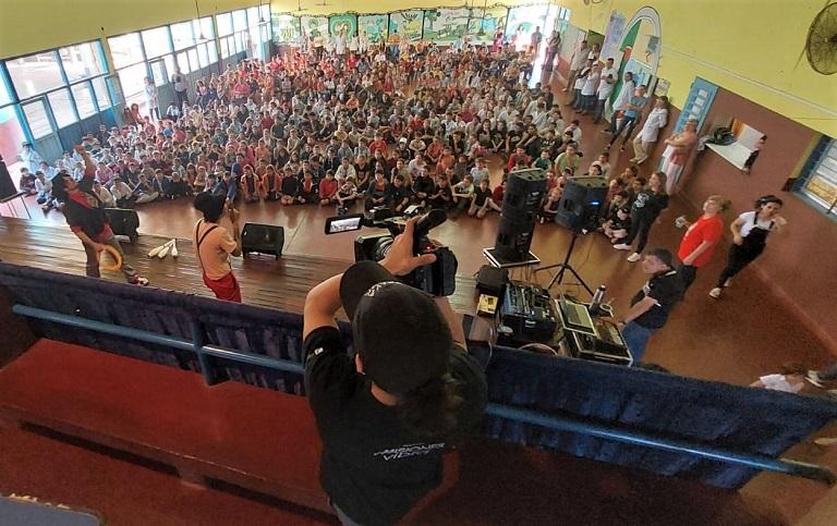 Camarógrafo (de espaldas) filma el show de Gurises Felices y a la multitud de niños desde atrás del escenario.