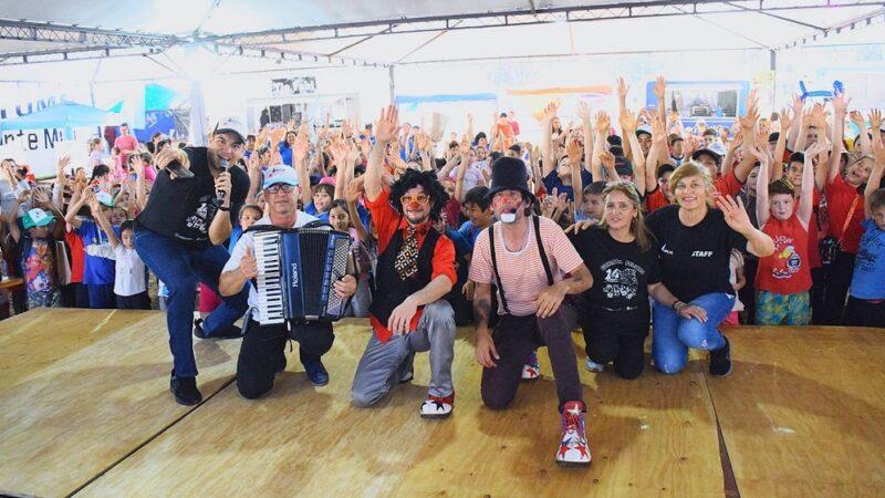 Equipo de Gurises Felices y multitud de niños saludan a la cámara, durante el Jeep Fest.