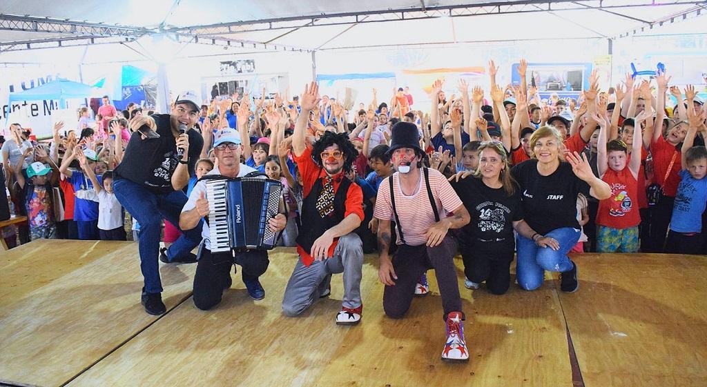 Equipo de Gurises Felices y multitud de niños saludan a la cámara, durante el Jeep Fest.