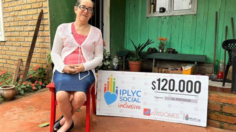 Verónica Gutiérrez muestra su cheque sonriente sentada frente a su casa.