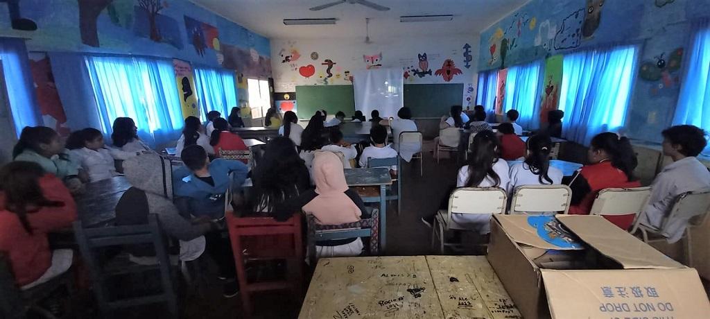 Alumnos de la Escuela 126 miran atentos un video durante charla de prevención de adicciones.