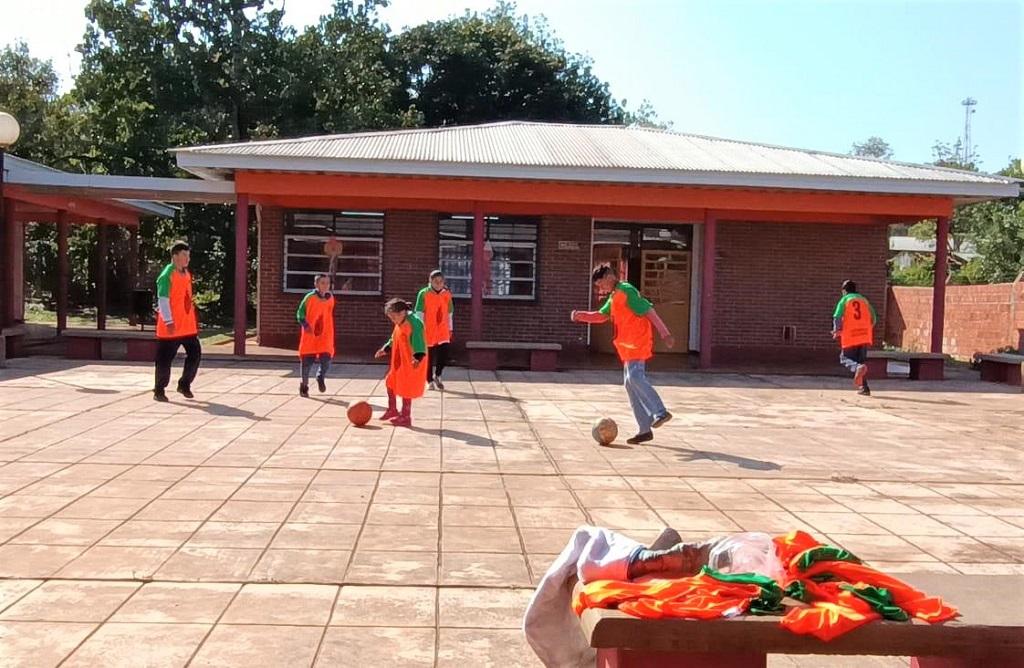 Alumnos de la Escuela de Educación Especial 40 juegan a la pelota con sus camisetas en el patio.