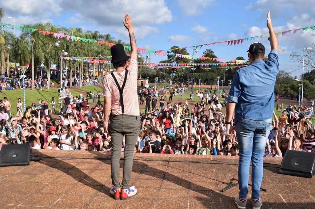 De espaldas a la cámara, Poca Sopa y Marcelo Ledesma saludan al público infantil, desde el escenario.