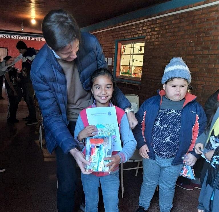 Niña recibe contenta un kit para pintar, de manos de Héctor Decut.