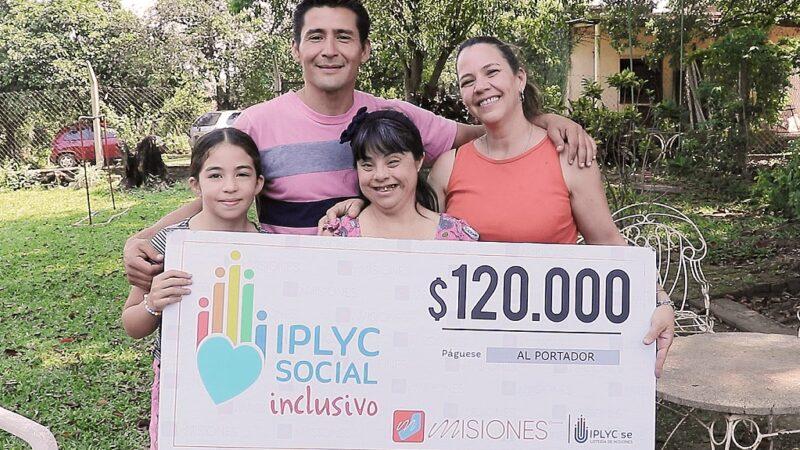 Rosana abrazada por su familia, y feliz, muestra su cheque.