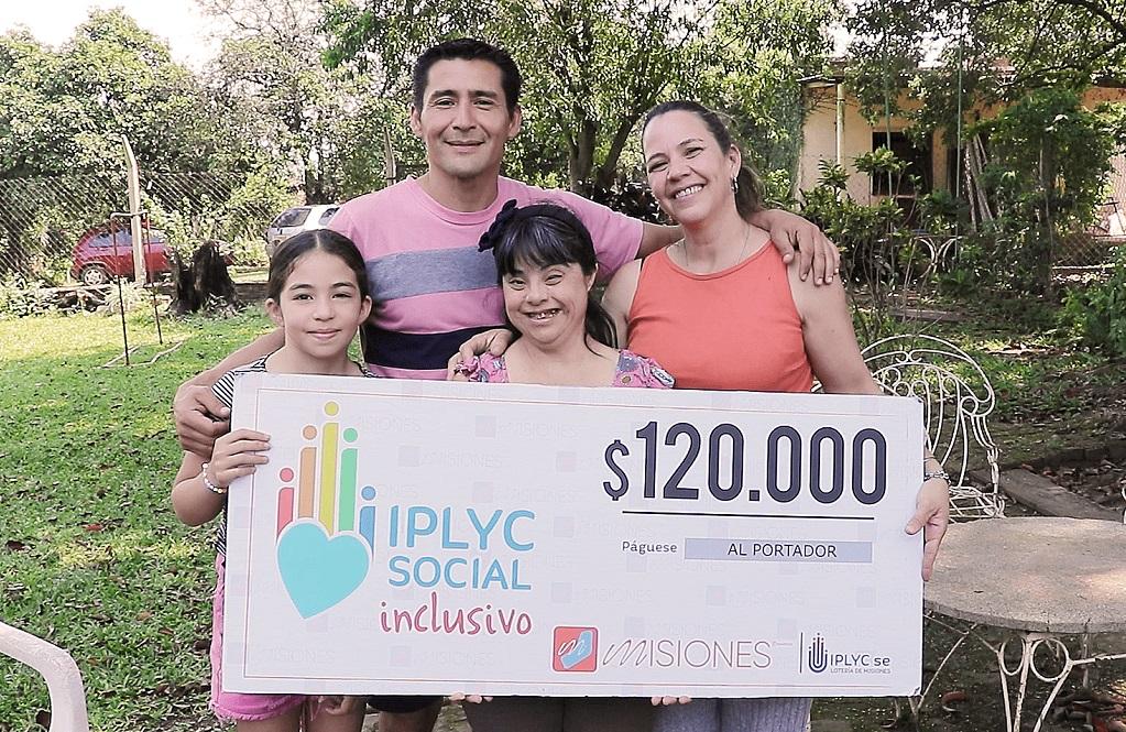 Rosana abrazada por su familia, y feliz, muestra su cheque.