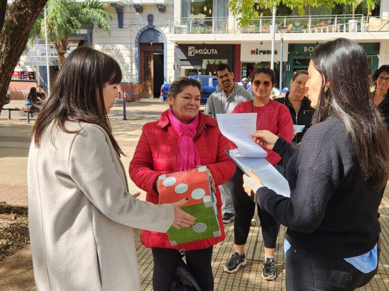 María Díaz Beltrán y Gabriela Peralta realizan un juego con dado gigante entre personas que transitan por la plaza,