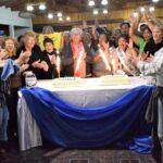 Reunión de abuelos en Eldorado. Abuelos cantan y aplauden alrededor de una mesa con tortas con velas encendidas.