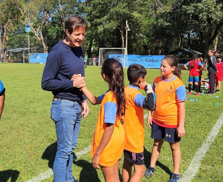 Héctor Decut y una niña integrante de un equipo se dan un apretón de manos de amistad.