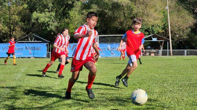 Niño corre tras la pelota secundado por otros de su equipo y el equipo adversario.