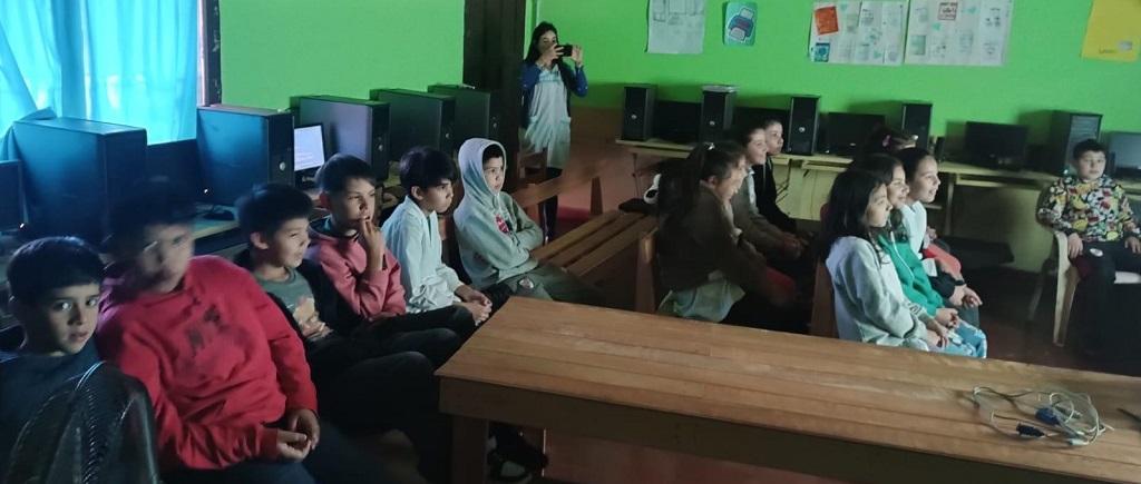 Alumnos de la Escuela 140 miran video durante la charla, junto a su docente.