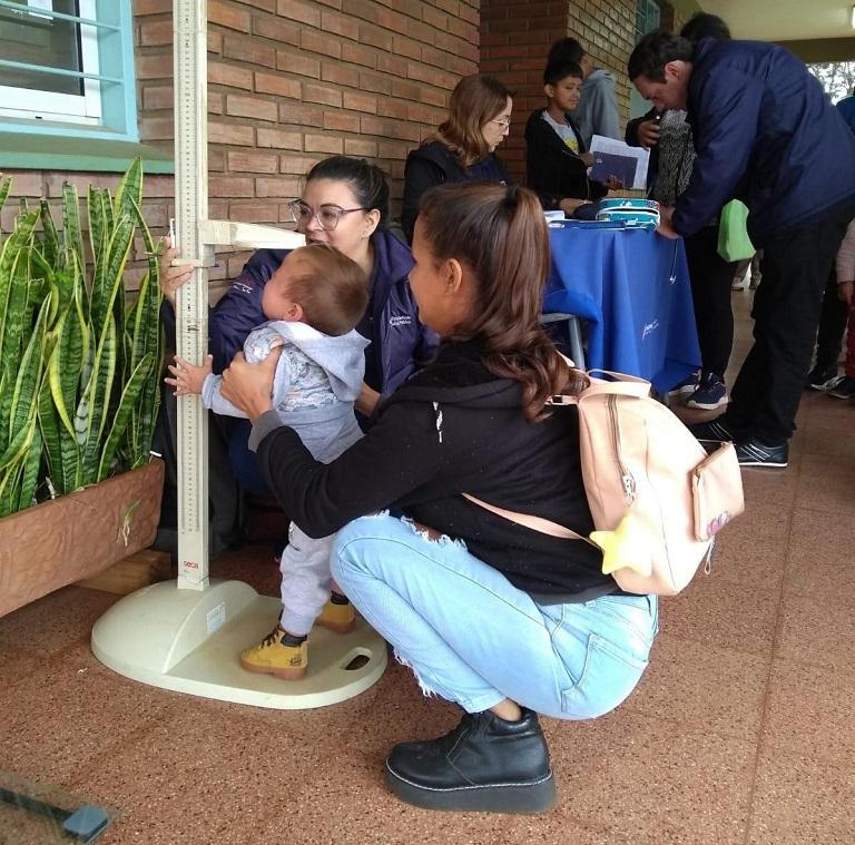 Colaboradora del programa realiza control de talla y peso a un bebé con ayuda de su mamá.