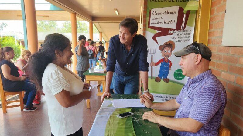 Vecina charla con Héctor Decut y un colaborador sobre huerta.
