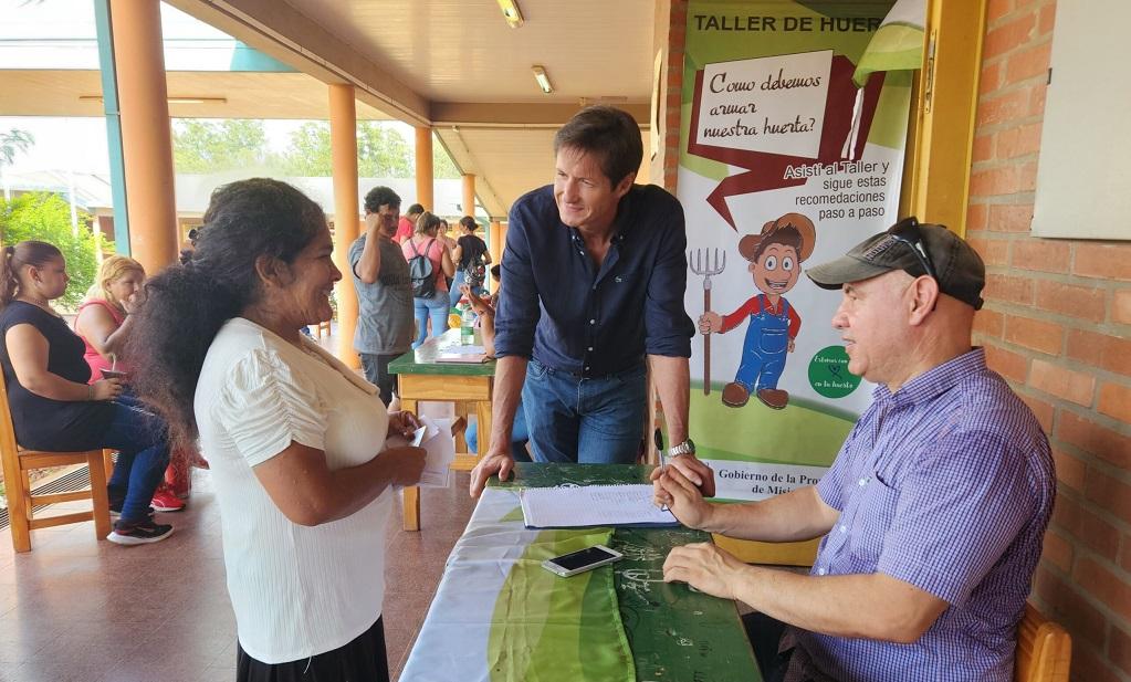 Vecina charla con Héctor Decut y un colaborador sobre huerta.