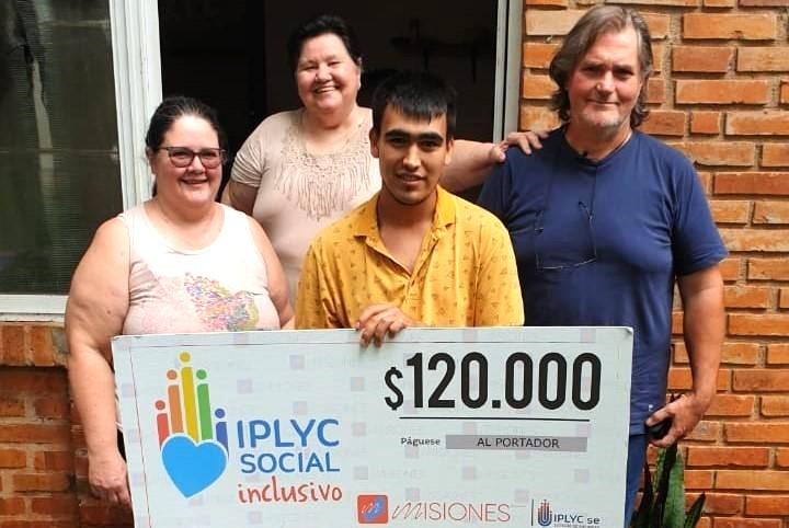 Lautaro junto a su familia muestran su cheque sonrientes. Usará el dinero para la compra de medicamentos.