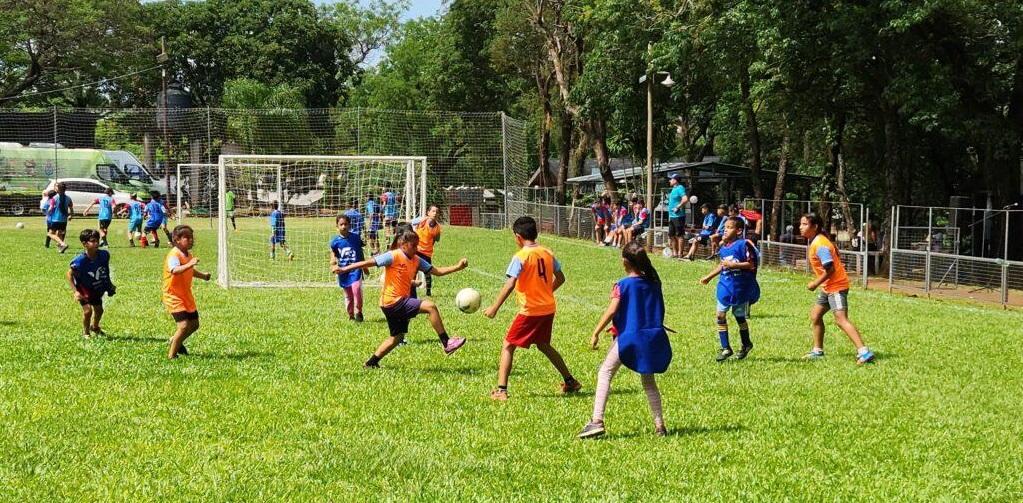 Equipos mixtos juegan un partido, niña lleva la pelota.