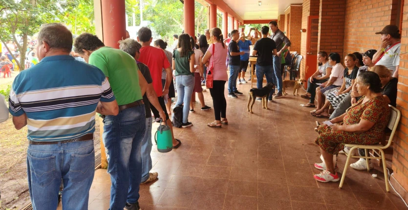 Vecinos hacen fila en la galería de la escuela esperando ser atendidos.