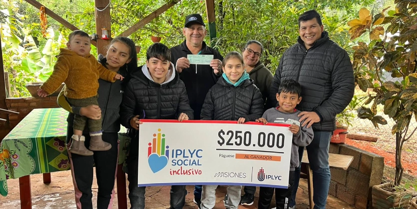 Calixto junto a su familia, sonrientes, muestran su cheque ganador del Inclusivo.