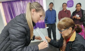 Colaboradora de "Mirar mejor" realiza control de vista a una vecina de Cerro Azul. Detrás, otros vecinos esperan a ser atendidos.