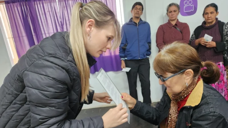 Colaboradora de "Mirar mejor" realiza control de vista a una vecina de Cerro Azul. Detrás, otros vecinos esperan a ser atendidos.