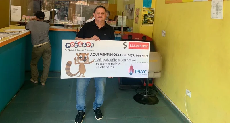 Nelson muestra el cheque ganador de la Poceada en el local de su Agencia 239 de Posadas.