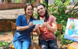 Stella junto a su hermana muestra felìz su cheque de IPLyC Social Inclusivo.