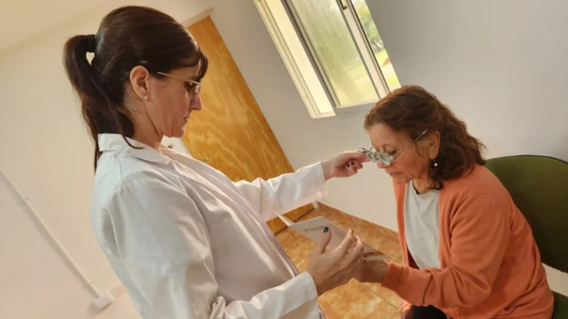 Mujer con lentes de prueba óptica lee un texto, asistida por una oftalmóloga del operativo Mirar Mejor.