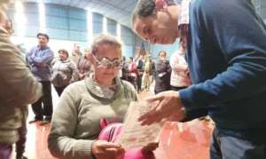 Señora con lentes de prueba óptica lee un texto, asistida por oftalmólogo. Operativo Mirar Mejor en San Javier.
