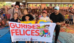 Equipo de Gurises Felices y tres niños muestran bandera del programa. Puerto Piray