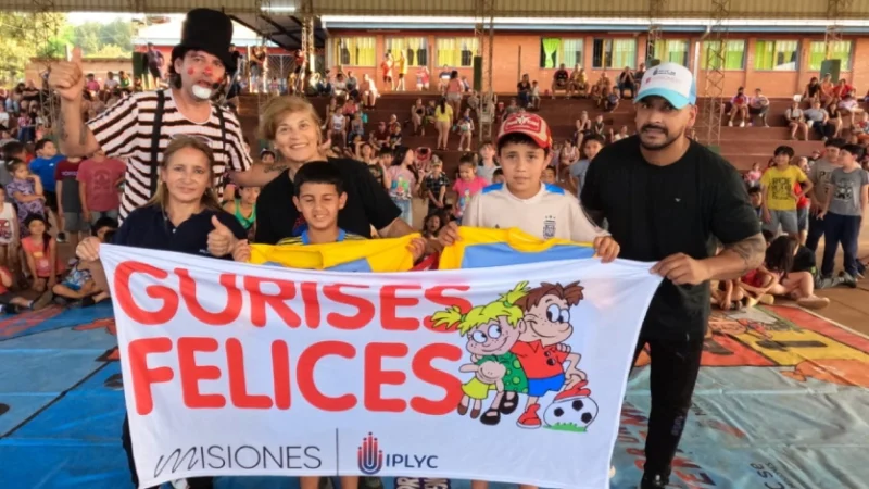 Equipo de Gurises Felices y tres niños muestran bandera del programa. Puerto Piray