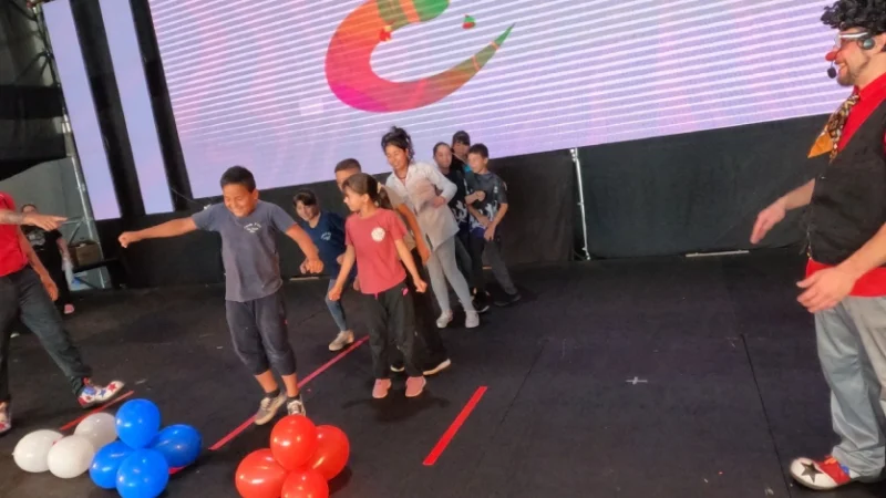 Niños hacen juego con globos junto a Tata Pó. Gurises Felices en la Fiesta de la Madera.