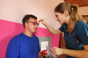 Oftalmóloga prueba graduación con lentes de prueba óptica a un joven. Mirar Mejor - Gobernador López.