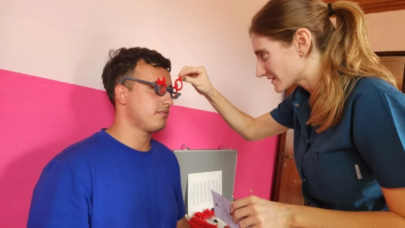 Oftalmóloga prueba graduación con lentes de prueba óptica a un joven. Mirar Mejor - Gobernador López.