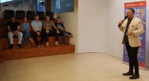 Ricardo Vera durante el sorteo del Deporbono 7, Héctor Decut y autoridades presentes observan en la sala de sorteo.