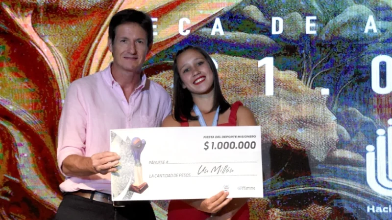 Héctor Decut junto a una deportista que recibe una de las becas.