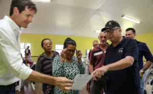 Decut y Passalacqua ayudan a una vecina a leer un texto de prueba con sus nuevos lentes. Mirar Mejor - Dos Arroyos.