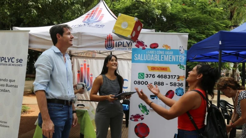 Héctor Decut y equipo de Juego Responsable juegan con dado gigante con una mujer en la plaza.