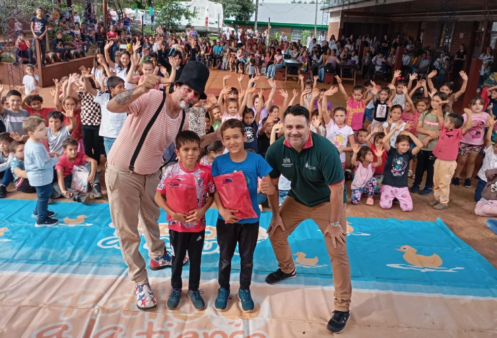 Poca Sopa junto a los niños con sus obsequios saludan a la cámara.