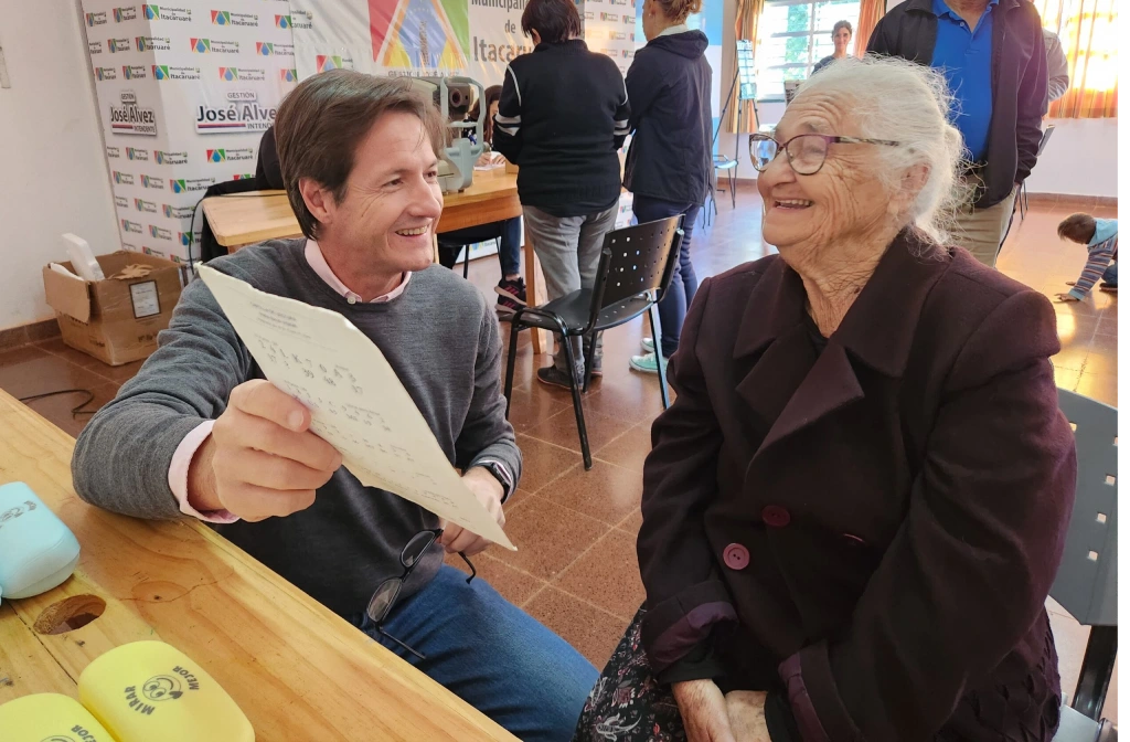 Abuela lee con sus nuevos lentes de Mirar Mejor junto a Héctor Decut en Itacaruaré.