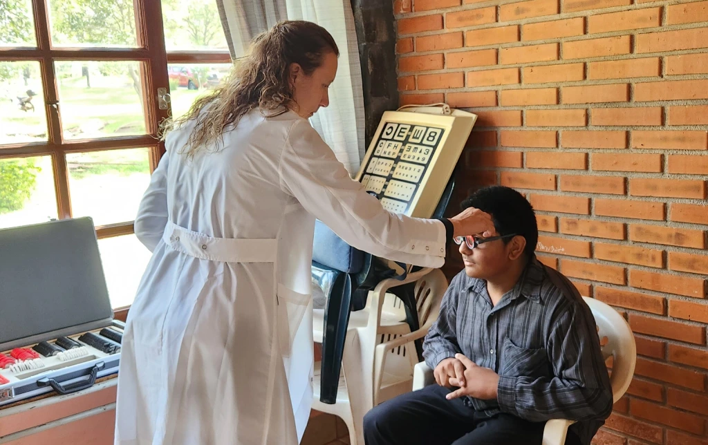Oftalmóloga prueba graduación de lentes a un joven.