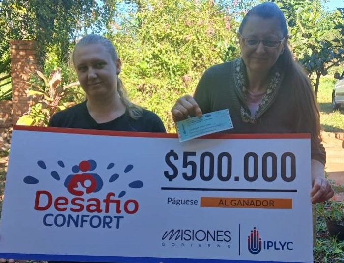 Liliana y su hija felices con su cheque. Usará el premio para operarse de cataratas.