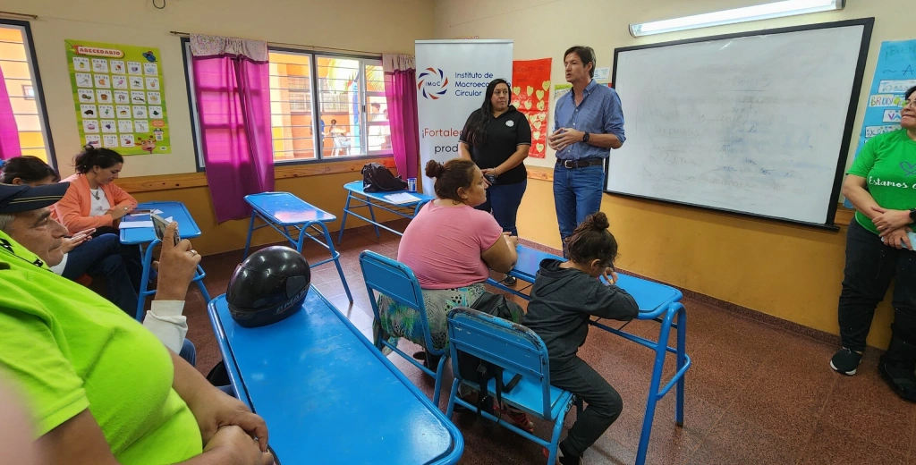 Héctor Decut y una colaboradora charlan con vecinos en un aula.