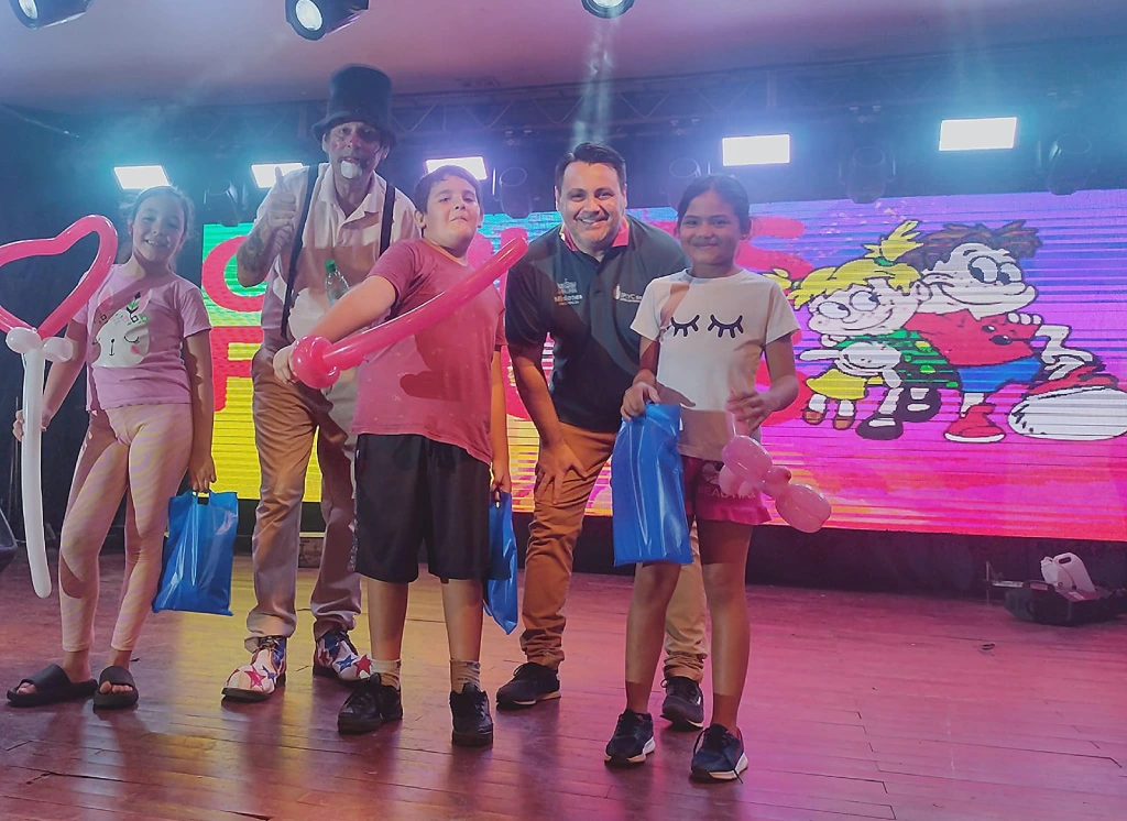 Poca Sopa y Marcelo Ledesma junto a tres niños felices con sus obsequios. Gurises Felices - IPLyC Social.