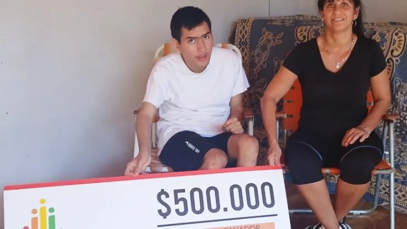 Cristian y su mamá muestran felices su cheque del premio de IPLyC Inclusivo.