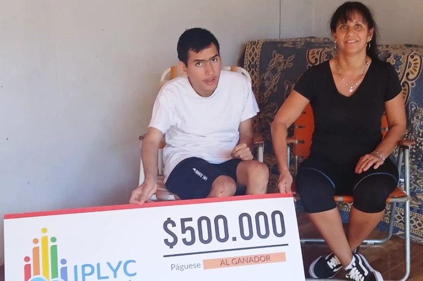 Cristian y su mamá muestran felices su cheque del premio de IPLyC Inclusivo.
