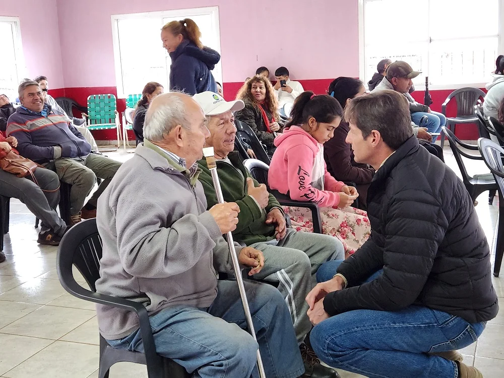 Héctor Decut charla con dos vecinos mayores mientras esperan a ser atendidos.